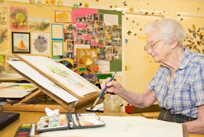 Elderly woman painting in a common area