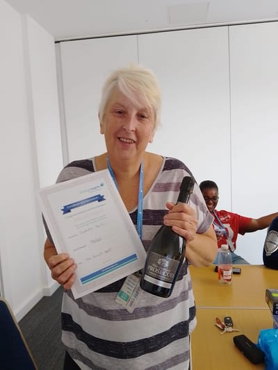 Staff member celebrating with certificate and prosecco.