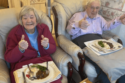 Residents enjoying a meal and giving thumbs up.