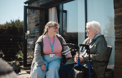 Two women conversing outdoors on a sunny day.