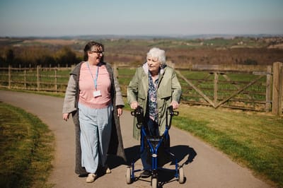 Staff member assisting resident outside on a path