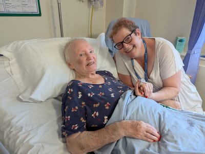 Resident and caregiver smiling together in a facility room.