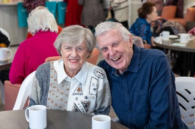 Happy seniors enjoying coffee together in a common area.