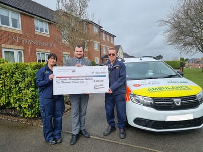 Staff presenting a check outside the facility