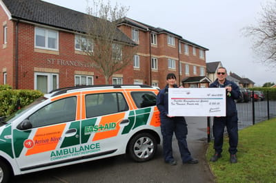Two responders with a large check outside a facility