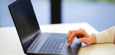 Close-up of a hand on a laptop keyboard.