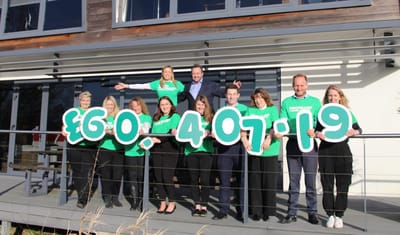 Group of people celebrating a fundraising achievement outside
