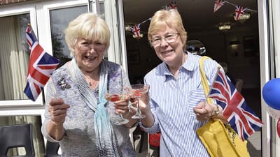 Two women celebrating with flags and drinks.