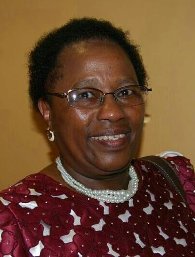 A woman smiling, wearing a red patterned dress.