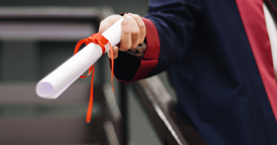 Individual holding a diploma with a red ribbon.