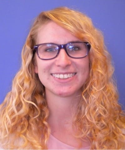 Smiling young woman with curly hair and glasses