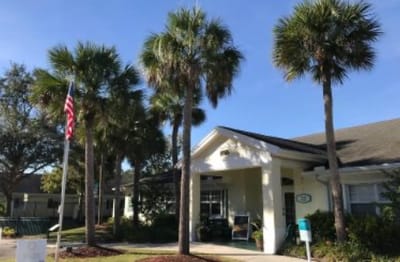 Front entrance of a senior living facility with palm trees