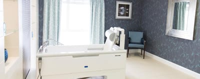 Brightly lit resident room with medical bed and chair