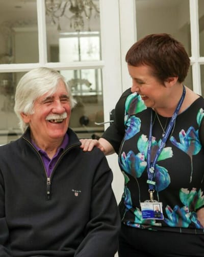A resident laughing with staff member in a cozy interior