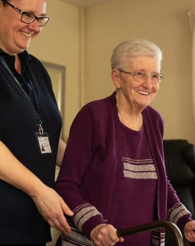 Care staff assisting a resident with a walker