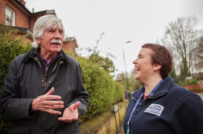 A staff member laughing with a resident outdoors