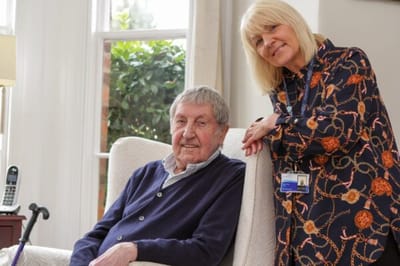 A resident and staff member smiling together indoors