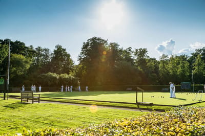Residents playing lawn bowls in a sunny garden