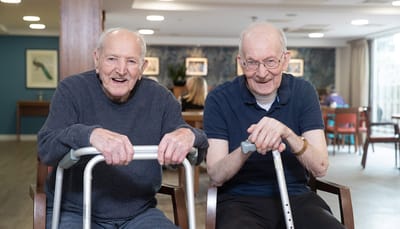 Two elderly men smiling in a common area