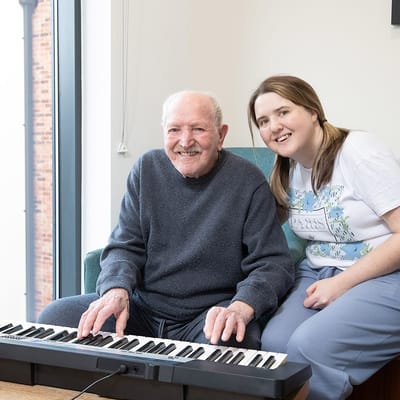 Resident and staff member smiling with a keyboard