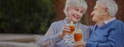 A couple smiling and toasting with drinks