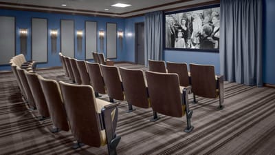 A cozy theater-style common area with chairs and a screen.