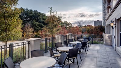 Patio area with tables and chairs surrounded by greenery