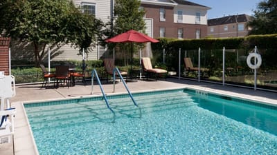 A pool area with chairs and umbrellas