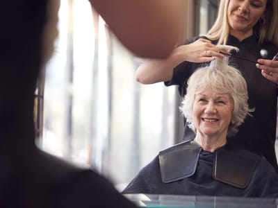 A senior woman getting her hair styled in a salon