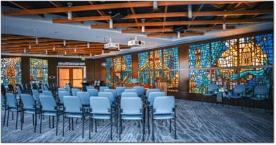 Bright event space with stained glass and chairs