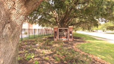 Signage for The Gardens of Bellaire surrounded by greenery