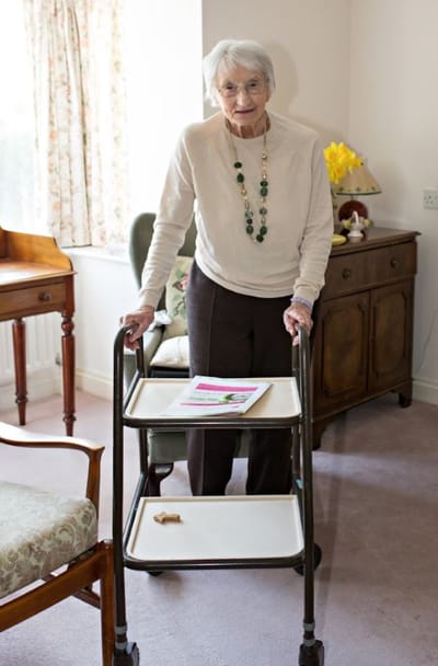 An elderly woman using a walker in a cozy room