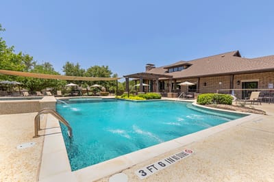 Outdoor pool surrounded by seating and lush greenery