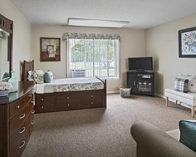 Brightly furnished private resident room with a bed and seating area