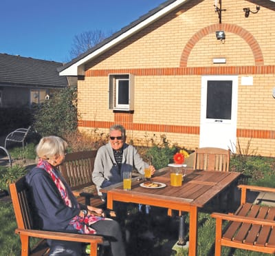 Two residents enjoying drinks outside a facility building