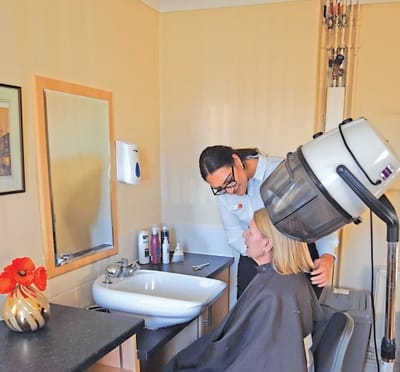 A staff member assisting a resident in a beauty salon