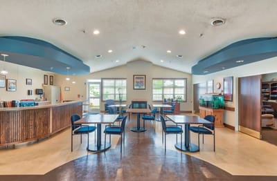 Bright common area with dining tables and a reception desk