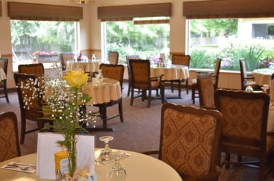 Dining area with tables set for meals and flowers.