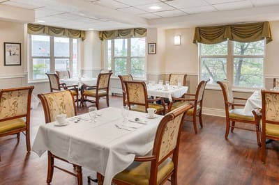 Dining area set with tables and chairs, bright windows