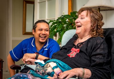 A caregiver laughing with a resident in a cozy setting