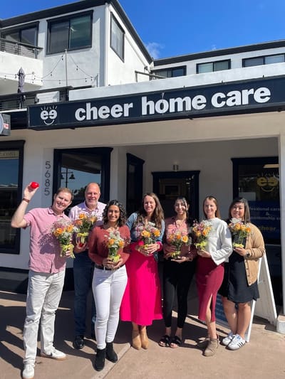 Staff members outside the Cheer Home Care facility holding flowers