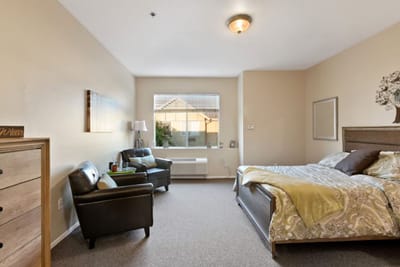 A cozy resident room with a bed and seating area