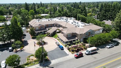 Aerial view of a senior living facility with gardens and parking