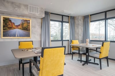 Bright common area with large windows and yellow chairs