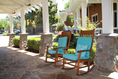 Outdoor seating area with rocking chairs and greenery