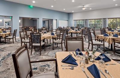 Dining room set up for a meal with tables and chairs