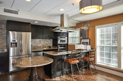 Modern kitchen area with bar stools and appliances