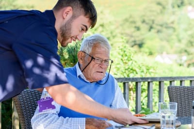 Staff serving food to an elderly resident outdoors