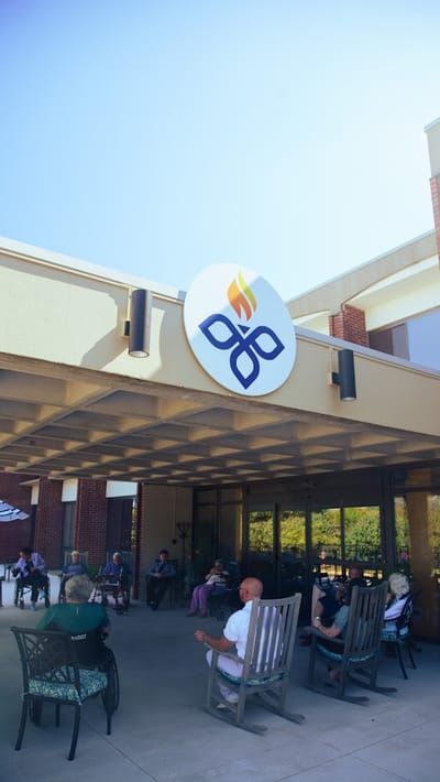 Building entrance with logo and residents outdoors