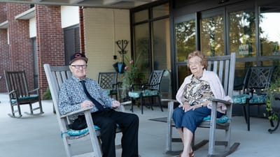 Two residents enjoying rocking chairs on a patio